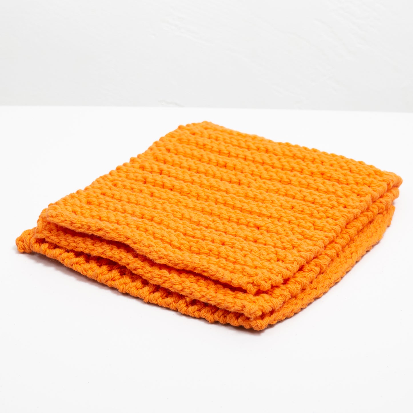 Three orange cotton wash cloths laid out on a white background.
