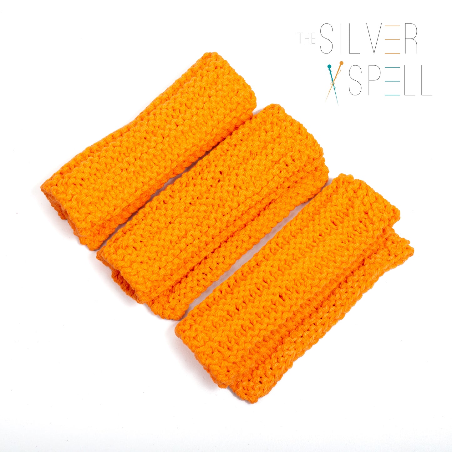 Three orange cotton wash cloths laid out on a white background.