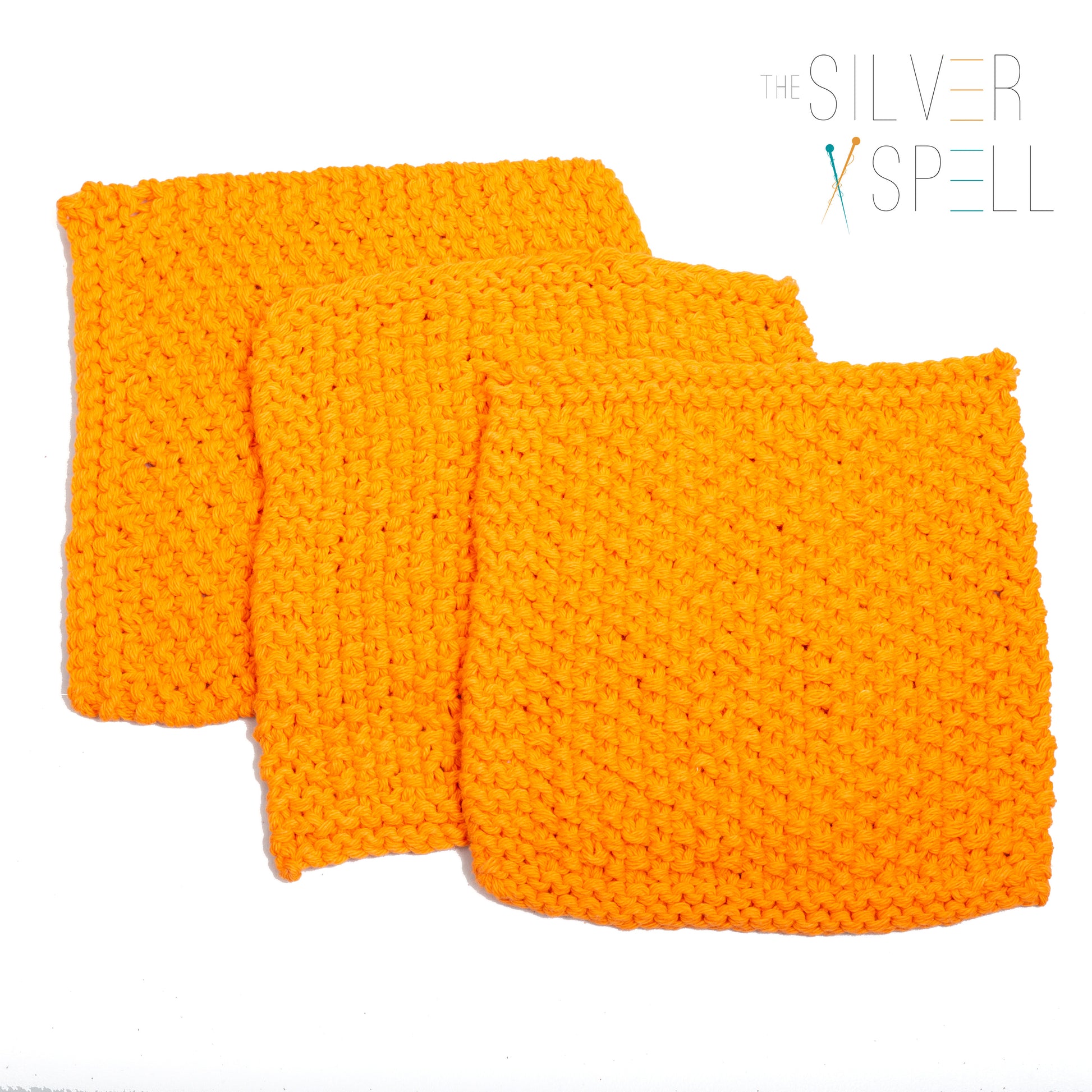Three orange cotton wash cloths with a crocheted pattern, displayed on a white background.