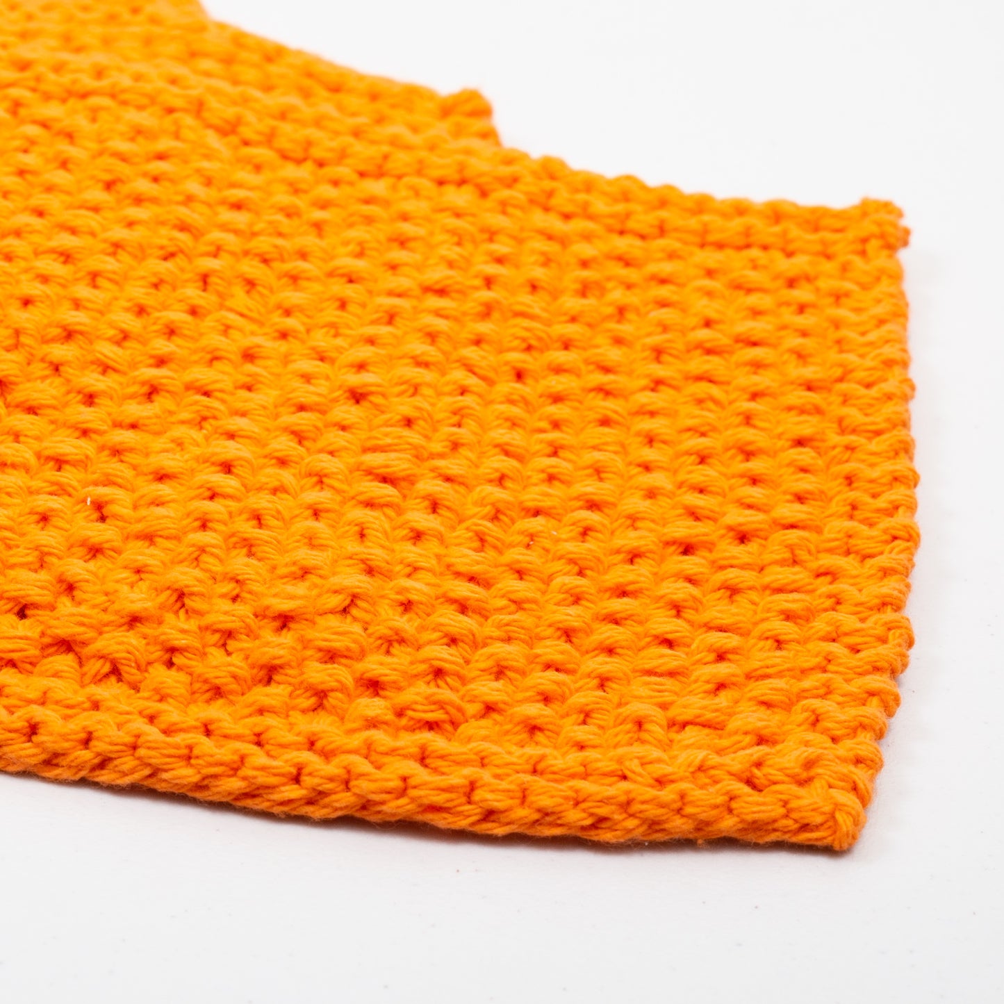 Two orange cotton wash cloths with a crocheted pattern, displayed on a white background.