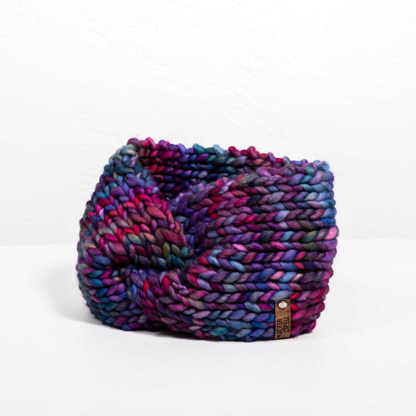 A multicolored hand-knit wool headband on a white background.