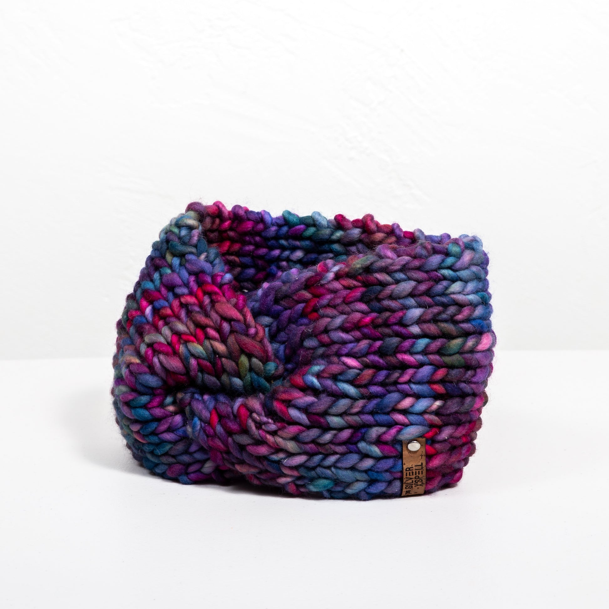 A multicolored hand-knit wool headband on a white background.
