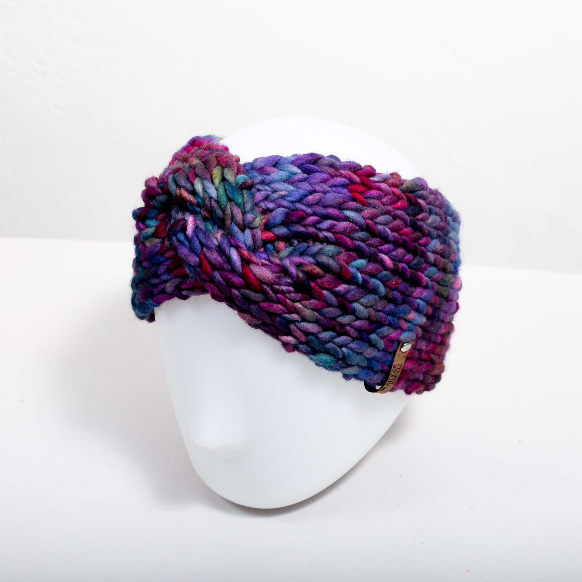 A multicolored hand-knit wool headband on a head mannequin